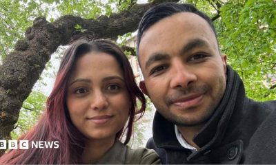 A selfie of a man and a woman sitting beneath a tree.