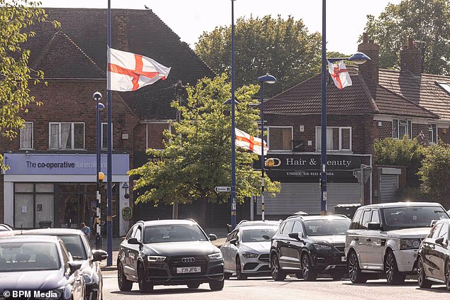 Multiple St George's and Union Jack flags are tied to lampposts around Weoley Castle in Birmingham