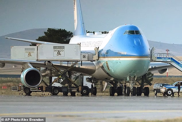 Catering trucks are parked at Air Force One on the tarmac as the motorcade carrying President Donald Trump arrives on the tarmac to depart following the NATO summit
