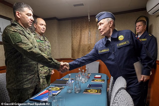 Vladimir Putin shakes hands with a navy officer, as Russian Pacific Fleet Commander-in-Chief Admiral Viktor Liina, right, stands near on the board of the Varyag missile cruiser, August 13