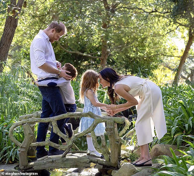 Pictured: Prince Harry hugging his son, Archie, while Meghan Markle holds their daugther, Lilibet's hands