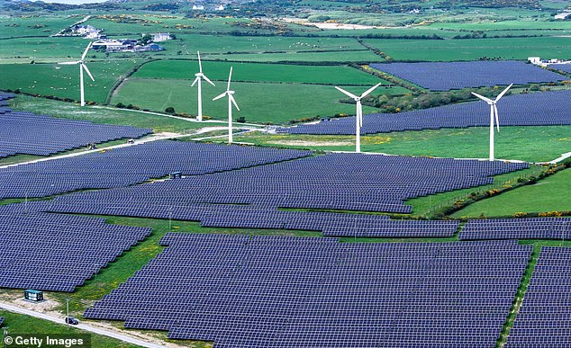 Wind turbines stand next to a solar farm near the Anglesey village of Rhosgoch in Wales