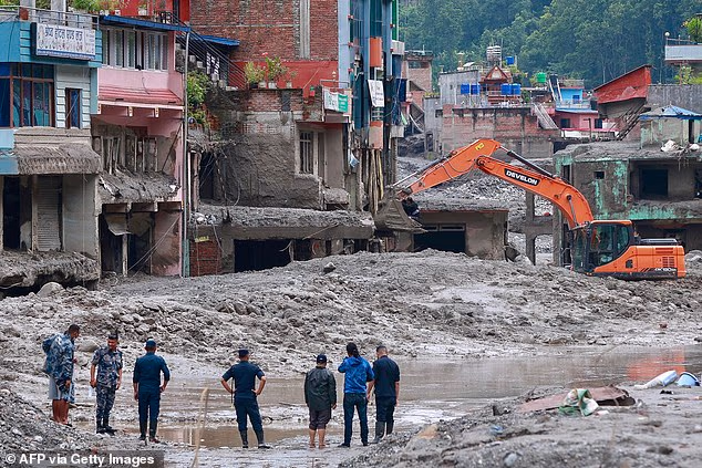 Workers use excavators to clear the mud at the Dhunge Bazaar in Nepal's Nuwakot district after flash floods and landslides hit