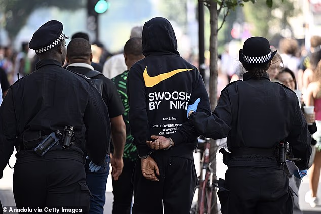 A man is led away in handcuffs by police at Notting Hill Carnival on Monday, the 'adults day' of the street festival