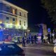 Police officers stand behind a cordon on a residential street in Clapham at night, with forensic tents and emergency vehicles visible near a pub as investigators examine the scene of a fatal shooting.