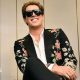 Milo Yiannopoulos wears a colourful suit with dark glasses and a white shirt.