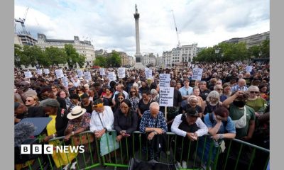 A crowd of people gather in Trafalgar Square as part of a vigil for Jason Arday. Some of them are holding placards.