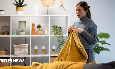 Woman arranging a warm, soft yellow blanket on a sofa