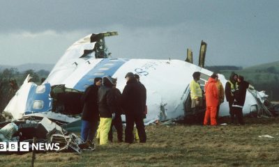 Emergency service workers stand next to the wreckage of Pan Am flight 103 in a field east of Lockerbie.