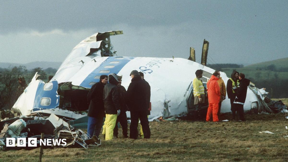Emergency service workers stand next to the wreckage of Pan Am flight 103 in a field east of Lockerbie.