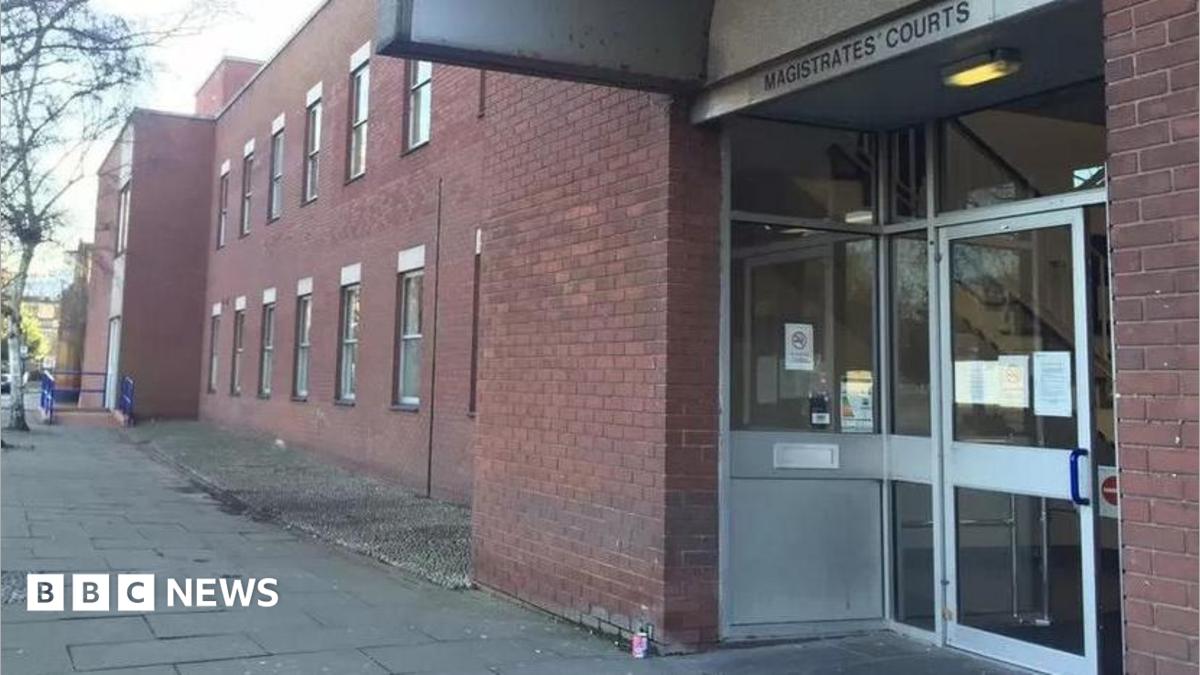 A red-bricked double-storey building with a large glass door. Above the door is a sign that reads: "Magistrates' Courts". There are paving slabs leading up to the entrance.