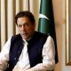 Former Pakistani Prime Minister Imran Khan speaks with Reuters during an interview, in Lahore, Pakistan March 17, 2023. He can be seen seated with his hand outstretched and speaking. Two Pakistani flags are behind him