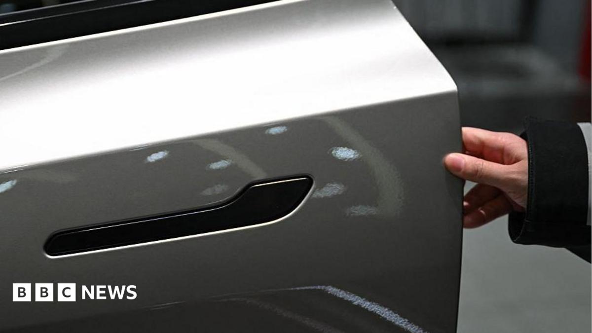 A customer inspects the minimalistic hidden door handles on an electric car in a showroom.