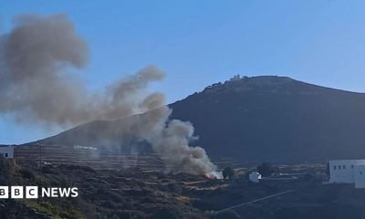 A few people are seen working at a blackened site on a mountain