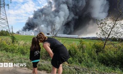 People watch as smoke rises above a Wildberries facility following a reported Ukrainian drone strike at the Koledino Industrial Park near Podolsk in Russia on 16 August.