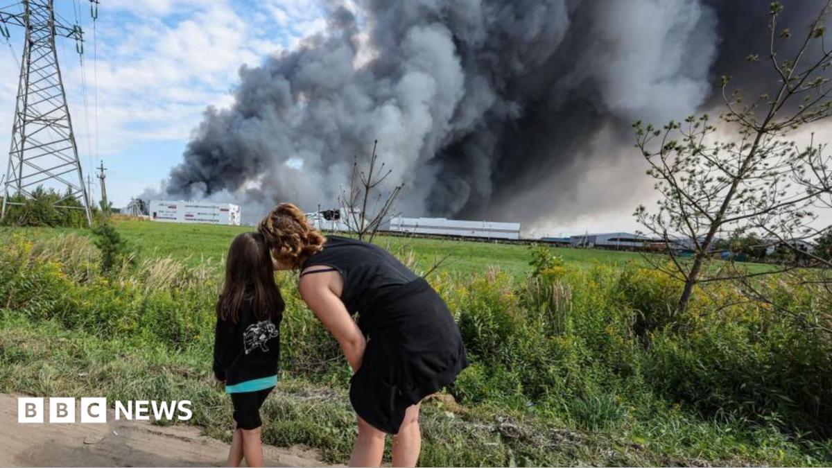 People watch as smoke rises above a Wildberries facility following a reported Ukrainian drone strike at the Koledino Industrial Park near Podolsk in Russia on 16 August.