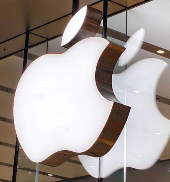Apple logo lit up on a sign on the glass windows of a storefront in China.