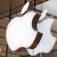 Apple logo lit up on a sign on the glass windows of a storefront in China.