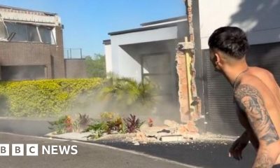 A topless man stands in the street while an earthquake damages buildings around him