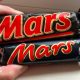 A Mars Bar from 1991 and a modern-day one held next to each other. The old Mars Bar is considerably bigger.