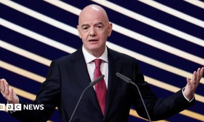 FIFA president Gianni Infantino speaks during an event, standing in front of a purple and yellow striped background.