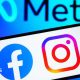 A phone screen with the facebook and instagram logos on it. In the background is the meta logo.