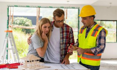 A couple looks at plans with a builder in their home, which is under renovation