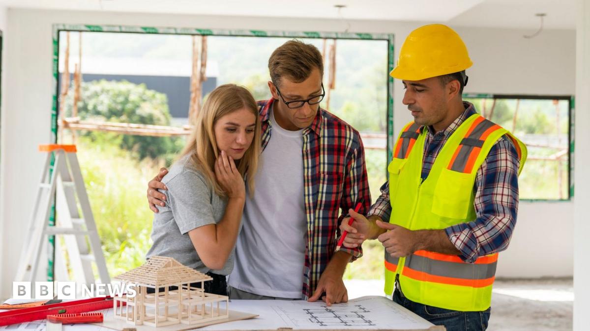A couple looks at plans with a builder in their home, which is under renovation