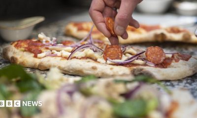 A robot arm hovers over a pizza