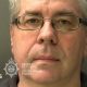 A mugshot of Christopher Phillips, who has grey hair and glasses