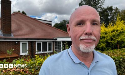 Man in a light blue polo shirt looks at the camera