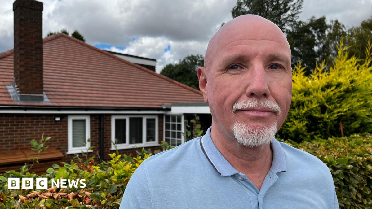 Man in a light blue polo shirt looks at the camera