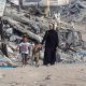 A Palestinian woman walks with children along a path lined with piles of rubble in the Sheikh Radwan neighbourhood of Gaza City