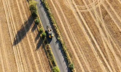 This aerial view shows a vehicle driving down a road with dried out farm fields on either side following months of little or no rain, in the village of Lullingstone, Eynsford, south-east of London on August 6, 2026.