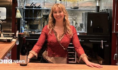 Caroline Kraetzer stands behind a bar, with her hands on the counter.