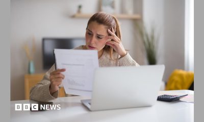 A woman with blonde hair looks at a bill