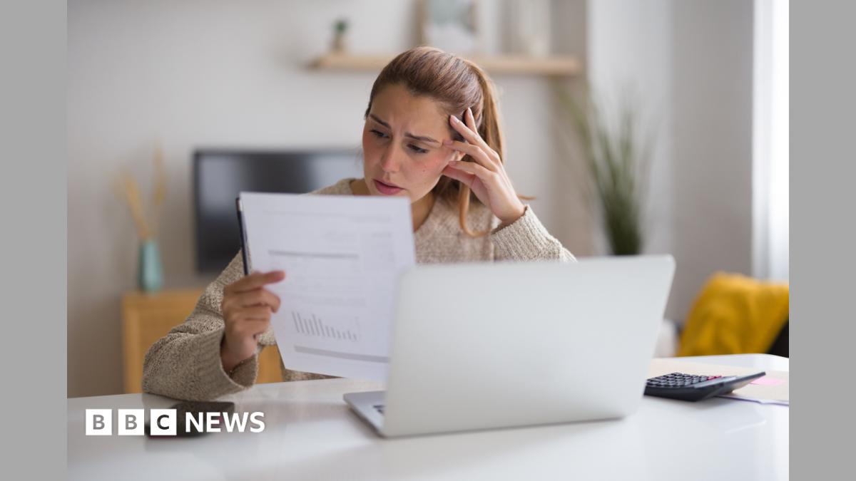 A woman with blonde hair looks at a bill