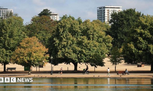 People walk, run and cycle through the parched park lands of Hyde Park during the drought in central London.