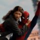 Spider-Man swings through the city on web whilst holding MJ, played by Zendaya.