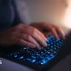 Close-up hands of female using laptop in bed at night