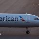 The front of an air plane with the American logo on a runway.