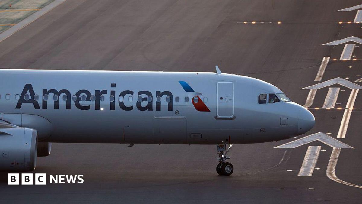 The front of an air plane with the American logo on a runway.