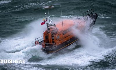 A Shannon class lifeboat in rough swell with a wave breaking over it.