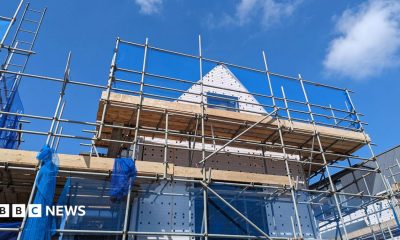 Stock photo shows the shell of a house with scaffolding around it against a blue cloudy sky, illustrating the building of new housing.