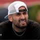 Nick Kyrgios, wearing a baseball cap backwards, looks out while slightly squinting