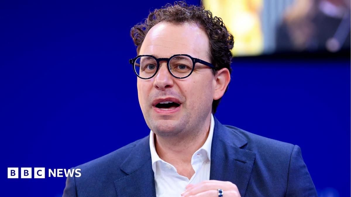 Anthropic CEO Dario Amodei speaking on a stage while gesturing with his hands.