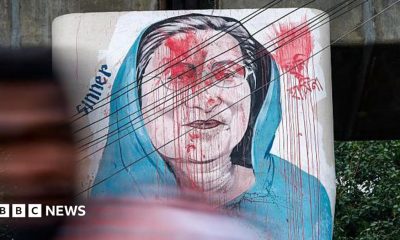 Vehicles move past graffiti depicting former Bangladeshi Prime Minister Sheikh Hasina in Dhaka