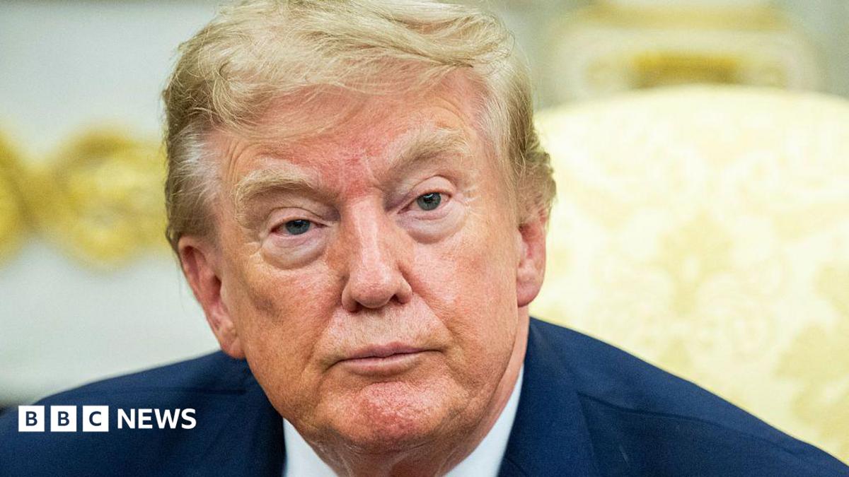 Donald Trump in a navy suit with a yellow background.