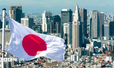 A Japanese flag flies in front of the Tokyo skyline