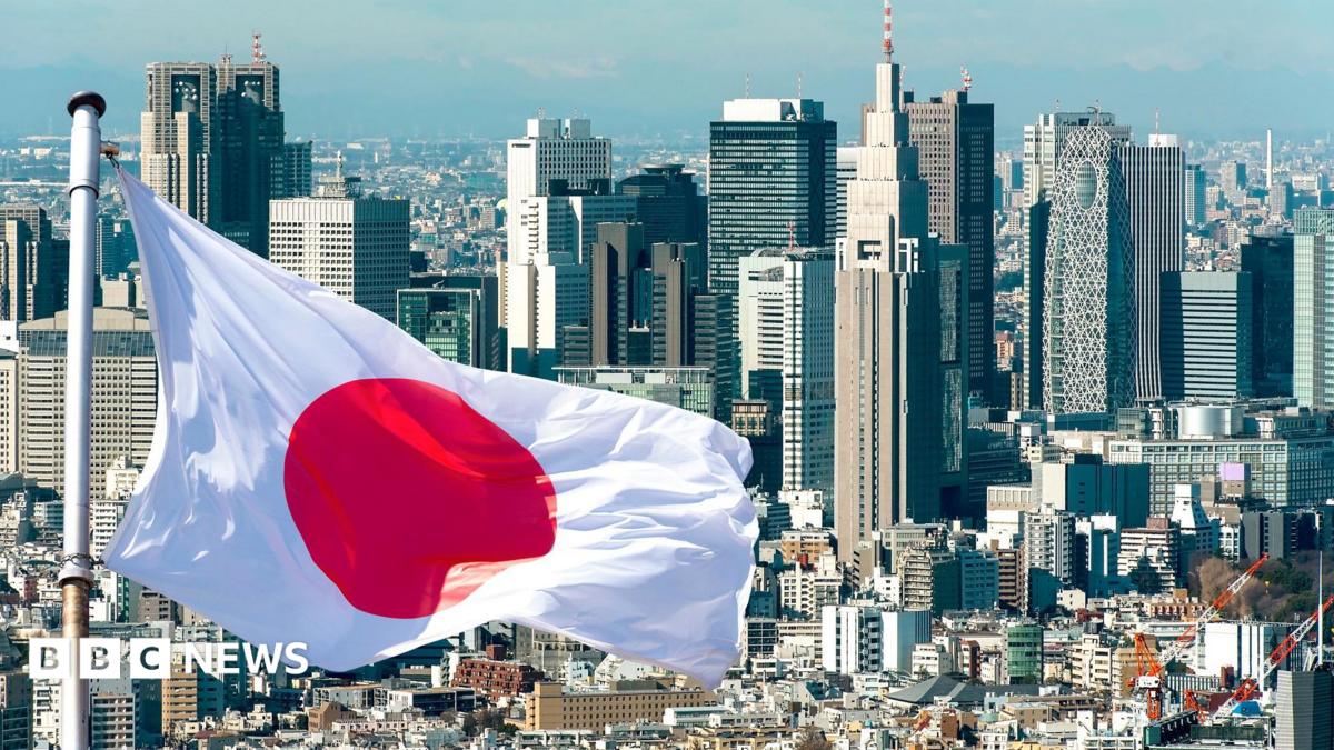 A Japanese flag flies in front of the Tokyo skyline